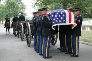 Soldiers carry casket during military funeral.