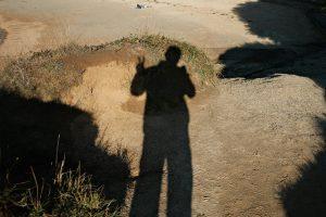 Shadow of a person making peace sign on ground