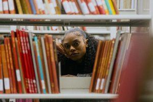 Young woman looking through bookshelves in a library